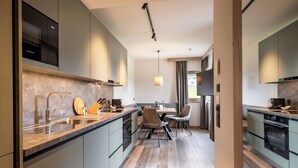 A modern kitchen with a built-in oven, a sink, and a dining area with chairs.