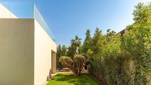 A modern building with a glass facade, a well-maintained lawn, and dense greenery. - Palais Eden (Marrakech)