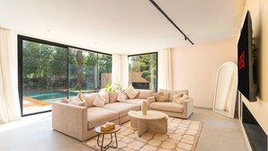 A modern living room with a large sectional sofa, a round coffee table, and a stone-patterned rug. - Palais Eden (Marrakech)