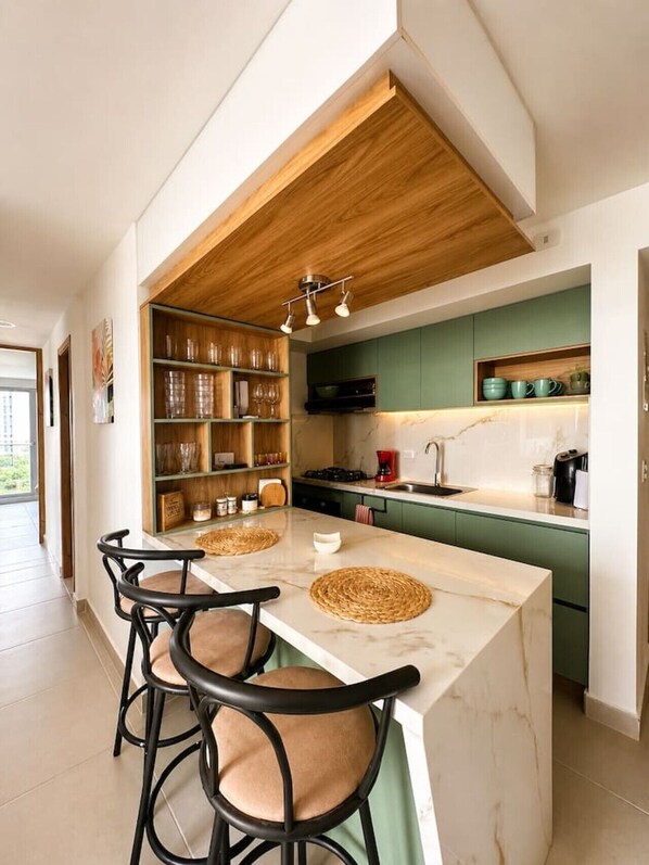 Een moderne keuken met een marmeren kookeiland, barkrukken en een houten plafond.