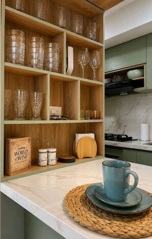 A kitchen with wooden shelves, a coffee maker, a book titled 'World of Wine,' and a blue mug on a woven mat. - Caribbean Deluxe • Pool, Views & WiFi (Cartagena)