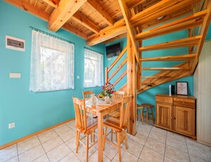 A room with a dining table, chairs, a kitchen area, and a wooden staircase. - Two-story Holiday Homes With Terraces, Playground (Mielno)