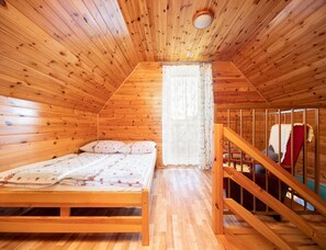 A wooden cabin bedroom with a bed, a window with curtains, and a wooden staircase. - Two-story Holiday Homes With Terraces, Playground (Mielno)