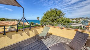 En balkon med udsigt til havet, en stol og et bord.