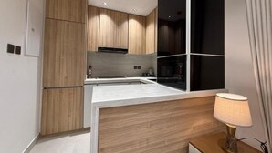A modern kitchen with wooden cabinets, a white countertop, and a built-in stove. - OrbitNet - Asasiat 36 (Madina)