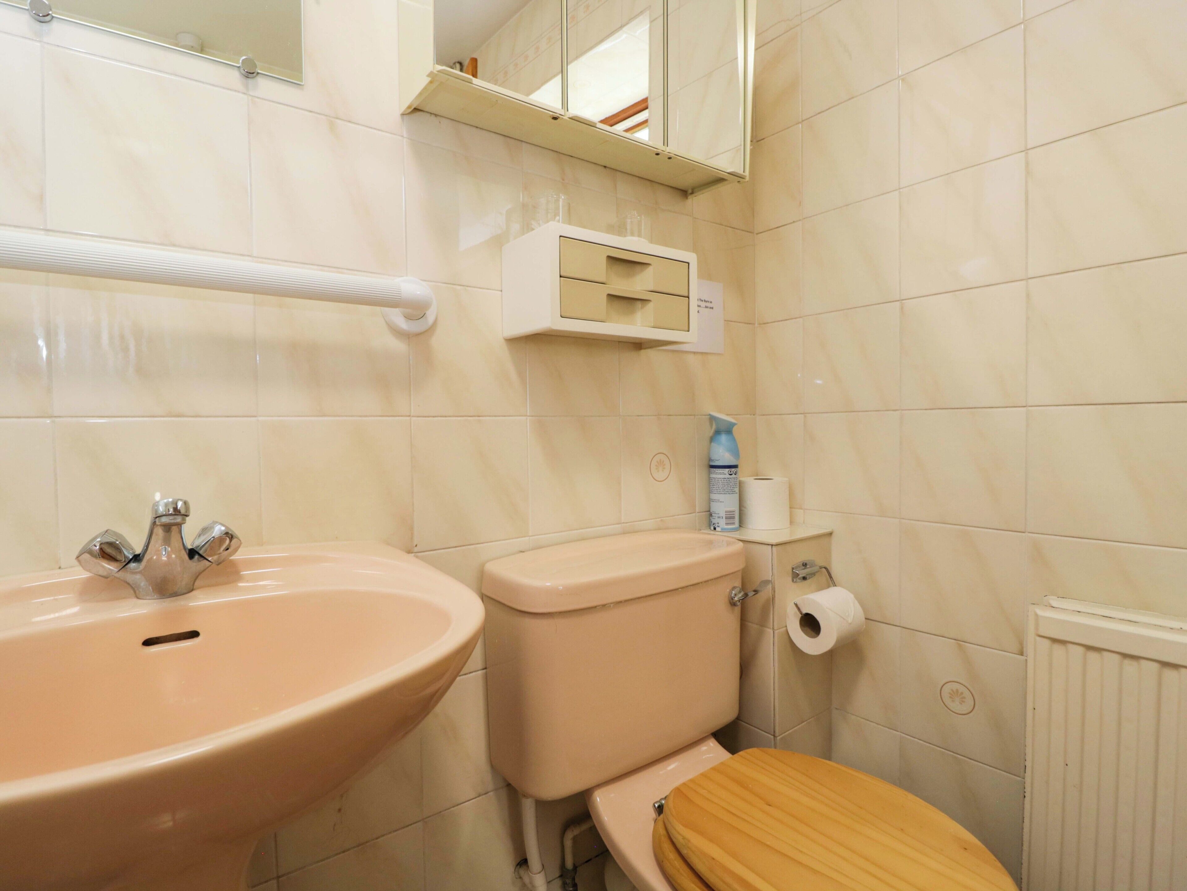 A bathroom with a sink, toilet, and mirror.