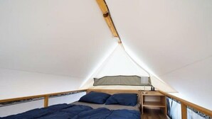 Une tente équipée d’un lit, d’oreillers et d’une petite table.
