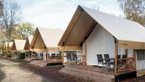Une rangée de tentes AADIS, dotées de terrasses en bois et de chaises.