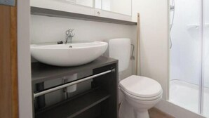 Une salle de bain avec un lavabo blanc, des toilettes et une douche.
