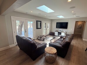 Una sala de estar moderna con sofás de cuero, una mesa de centro y un televisor.