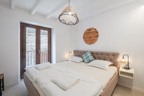 Un dormitori amb un llit gran, dues làmpades de nit, una decoració rodona de fusta a la paret i una finestra amb vista a arbres.