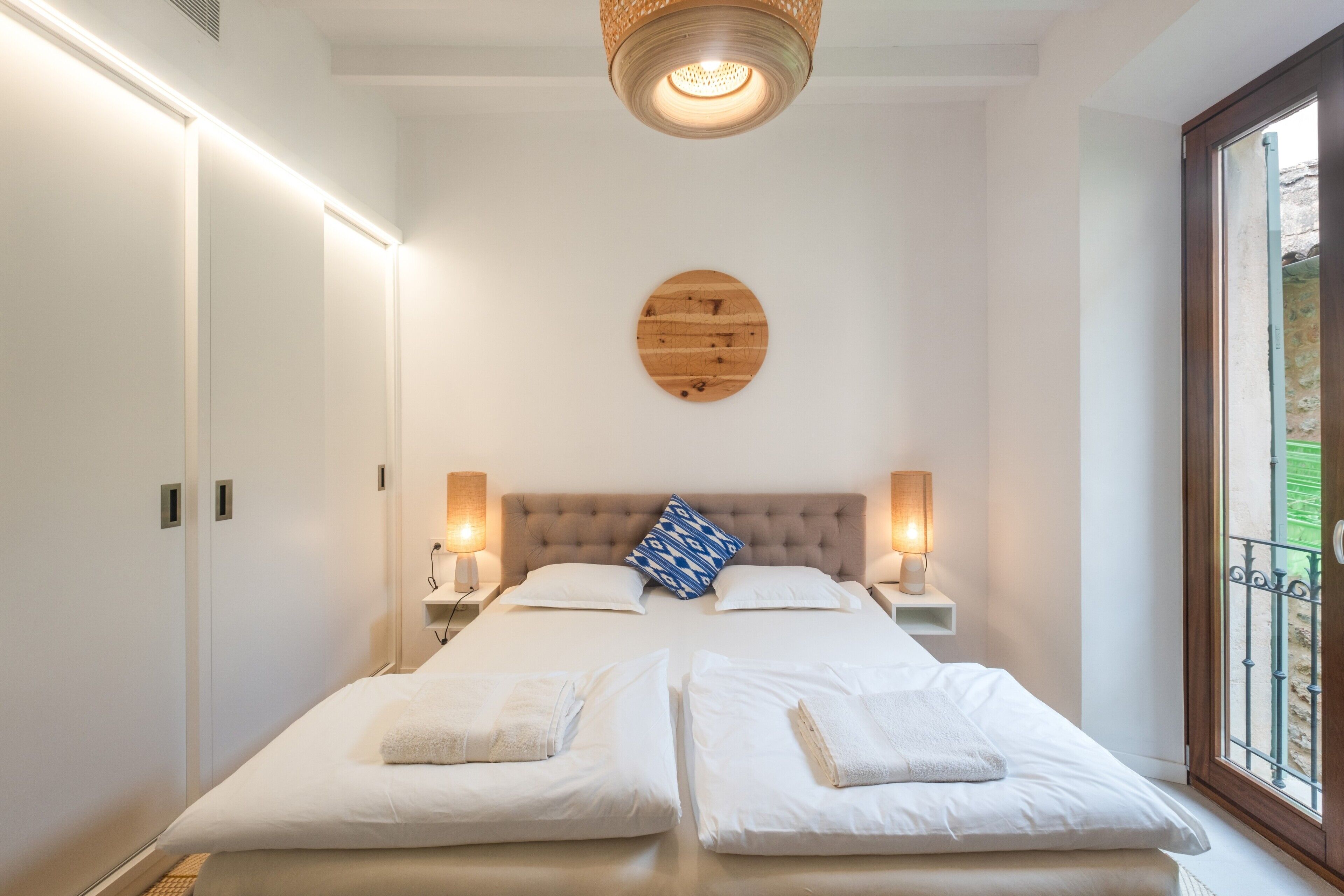 A double bed with two bedside tables, a wooden headboard, and a circular wall decoration.