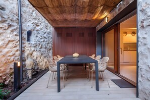 Een eethoek met een tafel en stoelen, een houten plafond en een stenen muur.