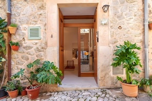 A stone building entrance with a wooden door, potted plants, and a stone-paved ground. - Holiday Home 'Rectoria 8' with Mountain Views, Wi-Fi and Air Conditioning (Valldemossa)