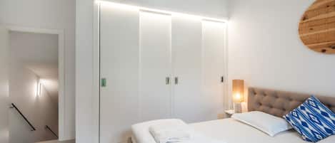 A bedroom with a bed, a bedside table with a lamp, a wardrobe, and a wall-mounted circular decoration.