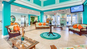 A lobby with teal walls, wicker furniture, and a large screen displaying 'Banquet'. - 2nd Floor Condo With Washer/dryer & On-site Pool, Dining - Near Theme Parks (Davenport)