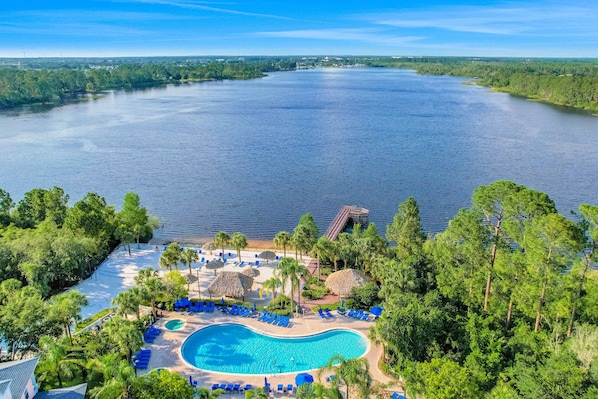 Un resort con una amplia piscina, sillas de descanso y vistas a un lago.