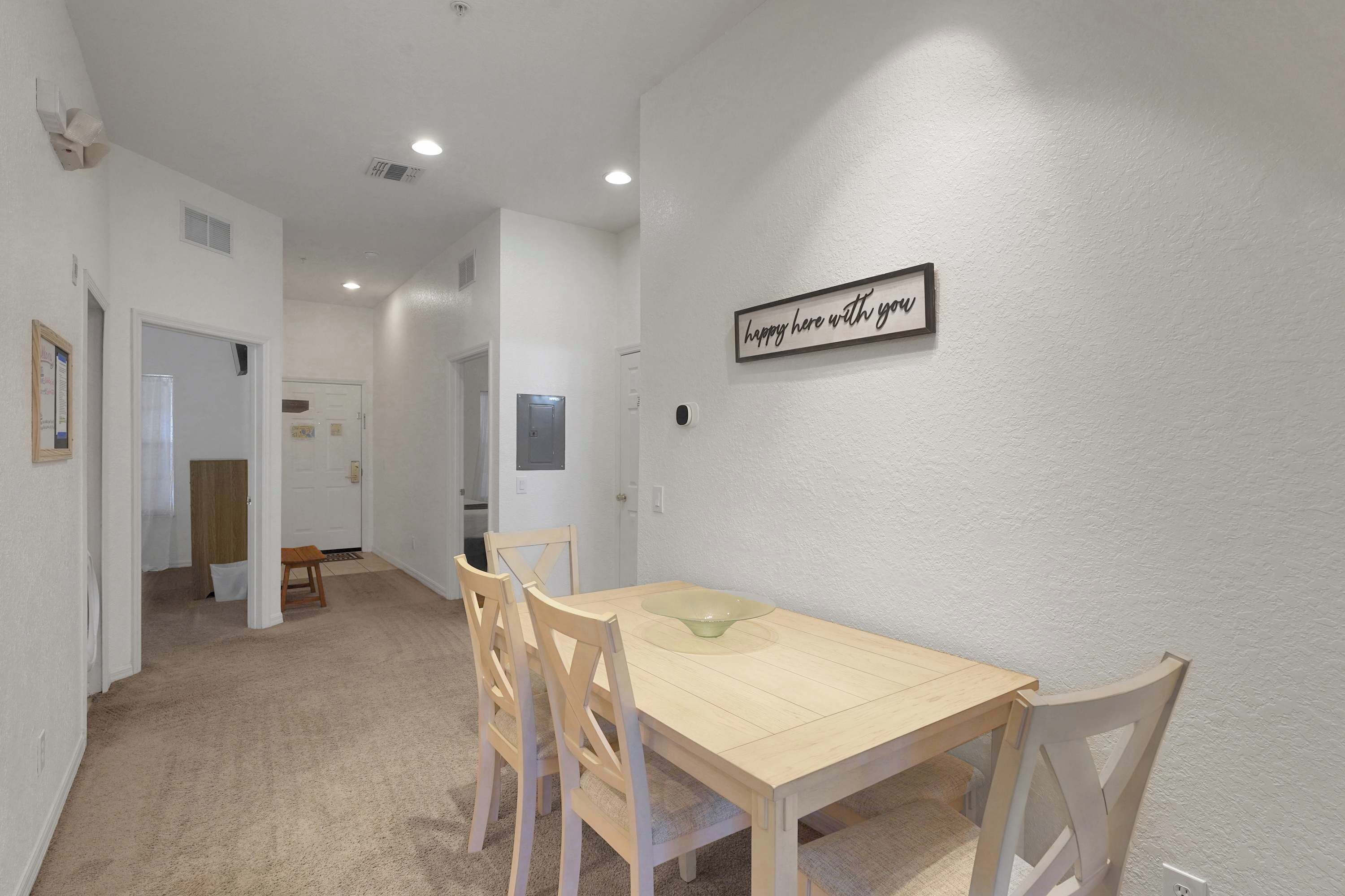 Un espace repas comprenant une table en bois, des chaises et un panneau fixé au mur.