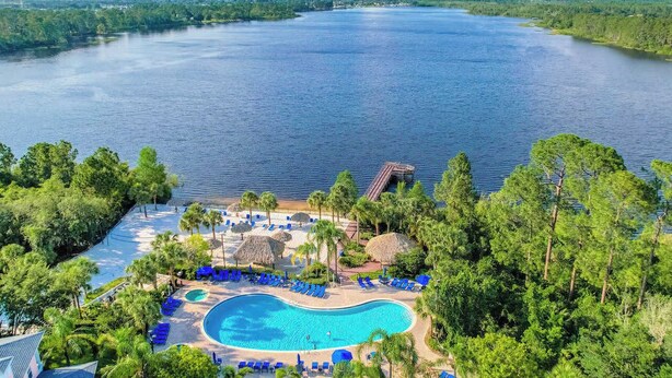Ein Resort mit großem Schwimmbad, Liegestühlen und Seeblick.