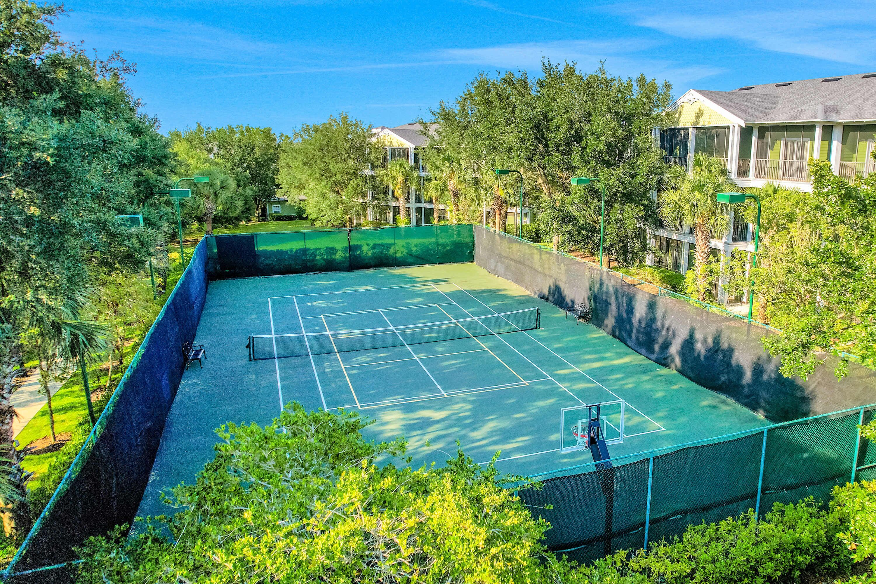 A tennis court surrounded by trees and buildings.