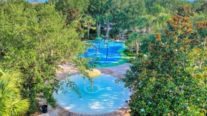 A water park with a pool, slides, and a circular water feature surrounded by lush greenery. - Beautiful Condo With Pool, hot Tub, Central AC & W/D - Short Drive to Disney (Davenport)