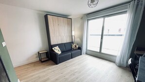 Ett modernt vardagsrum med en soffa, ett litet bord och ett stort fönster.