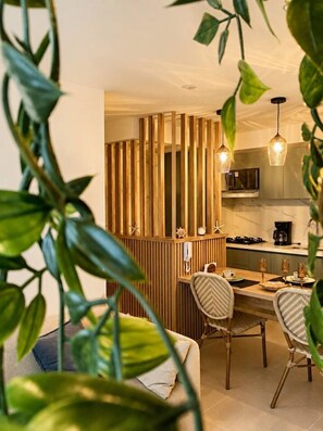 Eine moderne Küche mit einer Holzwand, einem Essbereich mit Korbstühlen und Pendelleuchten.