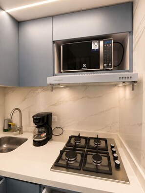 A kitchen with a microwave, coffee maker, and gas stove. - Mediterranean Suite | Sea View & Pool (Cartagena)