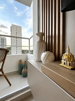 Ein Balkon mit Blick auf Gebäude, einem Stuhl und dekorativen Vasen.