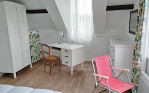A room with a white desk, a wooden chair, a pink folding chair, a wardrobe, and a window with sheer curtains. - Seaside house with cliff views (Piriac-sur-Mer)