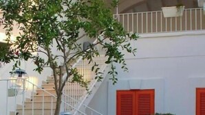 Una escalera con barandillas blancas, contraventanas rojas y macetas colgantes.