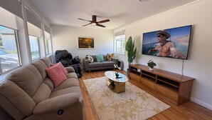 Un salon avec un canapé, une table basse, un téléviseur et un ventilateur de plafond.
