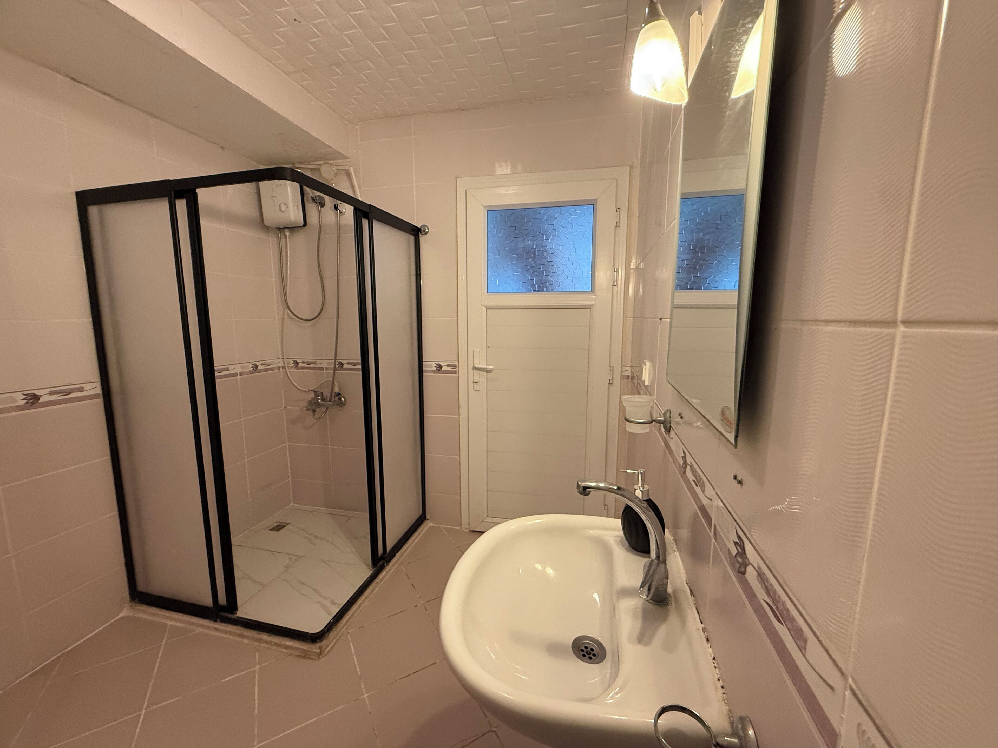 Un bagno con doccia vetrata, lavandino e specchio.