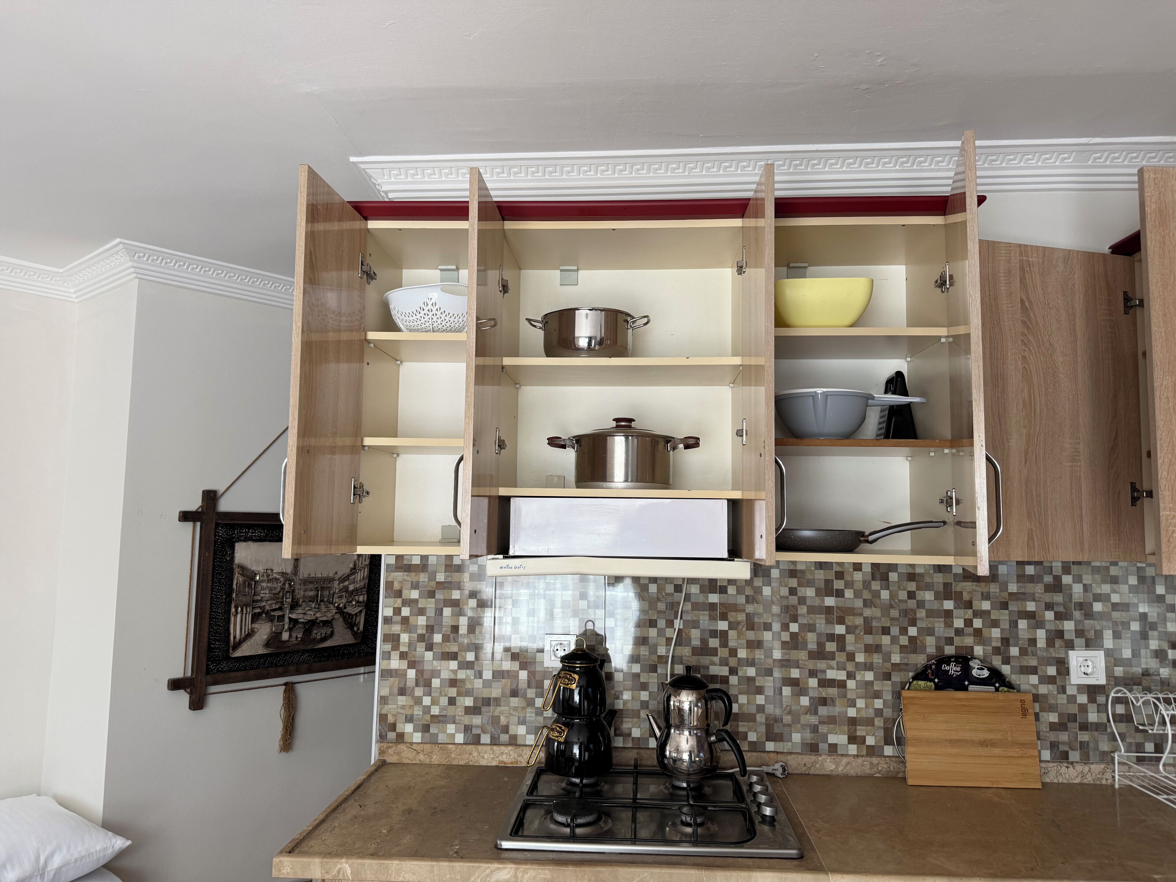 A kitchen with wooden cabinets, a gas stove, and a tiled backsplash.