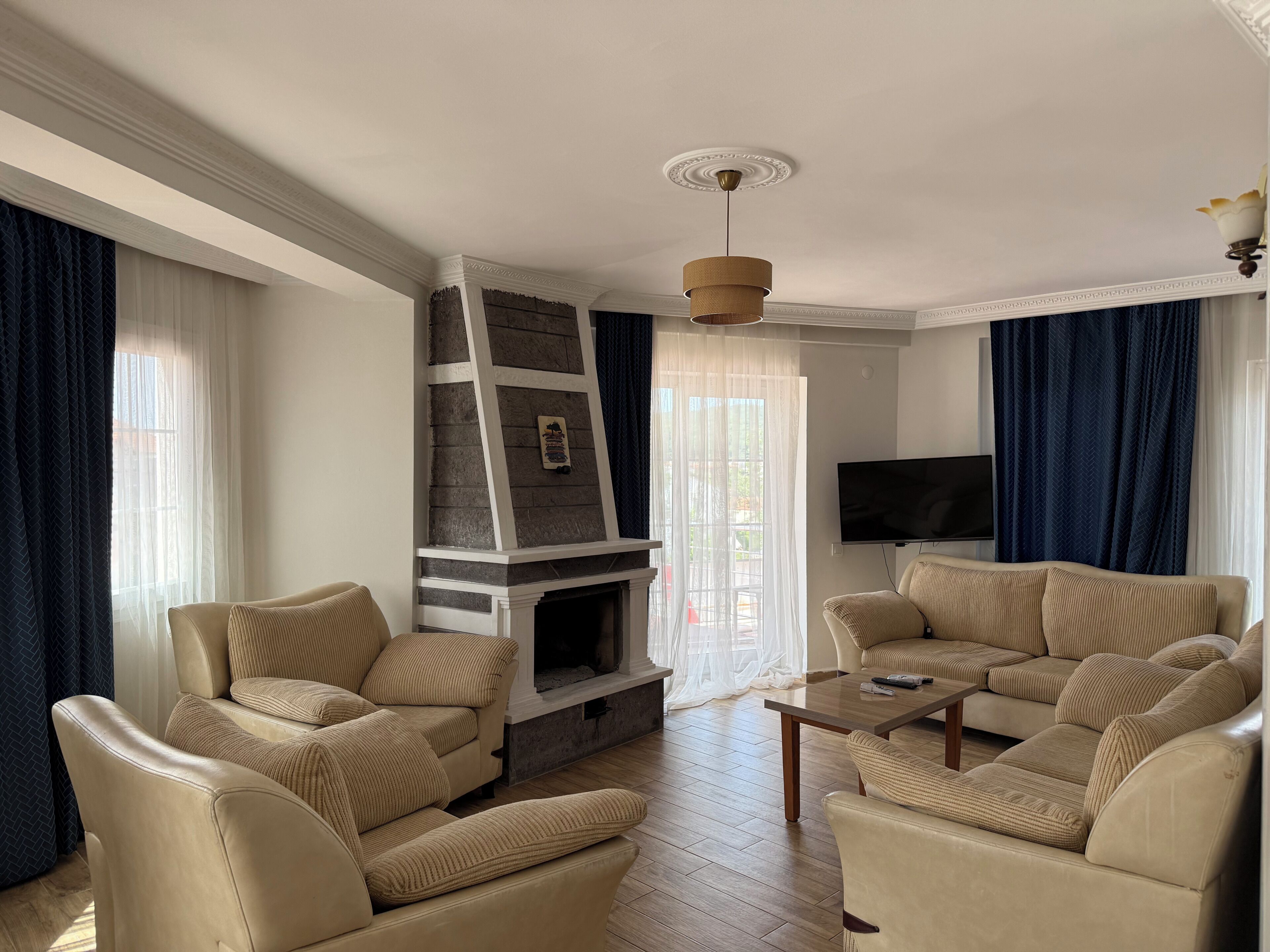 Un salon avec une cheminée, deux canapés de couleur beige, une table basse et un téléviseur fixé au mur.