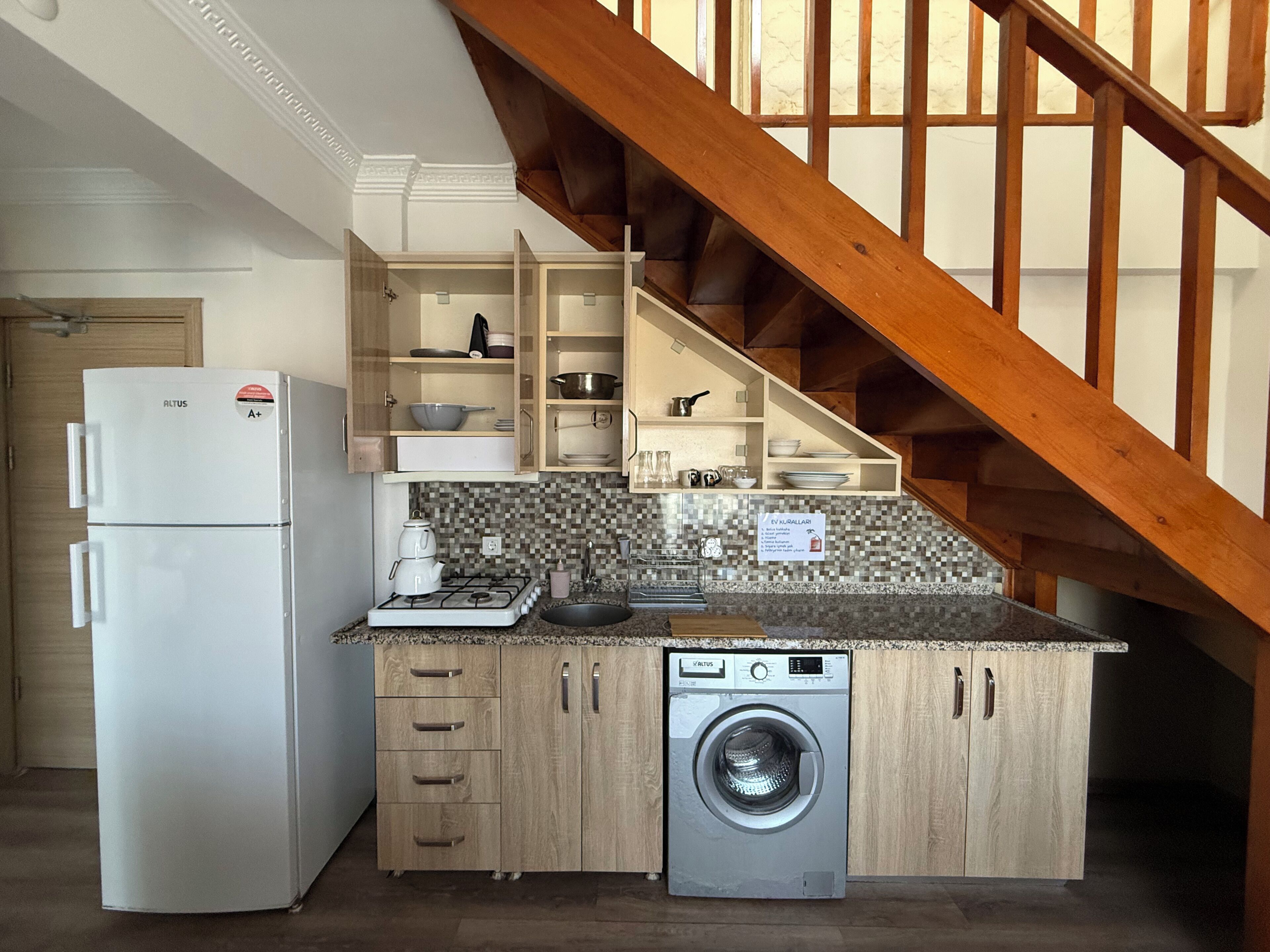 Una cucina compatta con lavatrice integrata, frigorifero e mobili in legno.