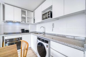 Eine moderne Küche mit weißen Schränken, Backofen, Geschirrspüler und Mikrowelle.
