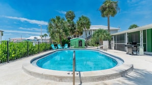 A swimming pool with a metal safety rail, surrounded by a concrete deck. - Dune Your Thing C (Fort Myers Beach)