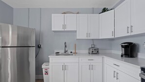 Eine moderne Küche mit weißen Schränken, einem Edelstahl-Kühlschrank, einer Kaffeemaschine und einem Toaster.