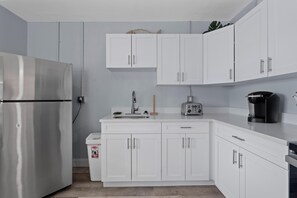 A modern kitchen with white cabinets, a stainless steel refrigerator, a coffee maker, and a toaster.