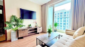 Una sala de estar moderna con televisor de pantalla plana, piso de madera, un sofá, una mesa de centro y plantas en macetas.