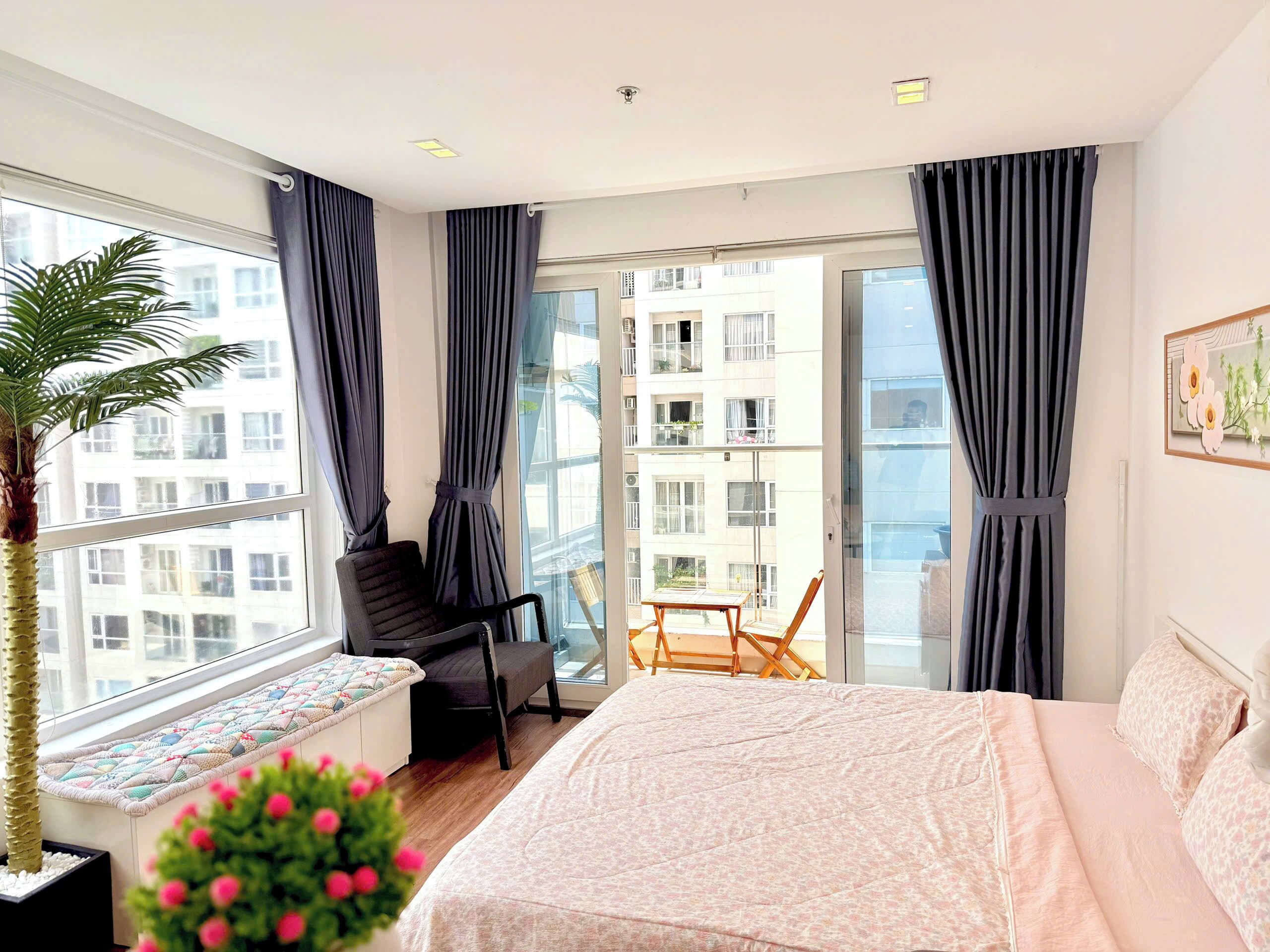 A modern hotel room with a large window, a bed, a chair, and a small table.