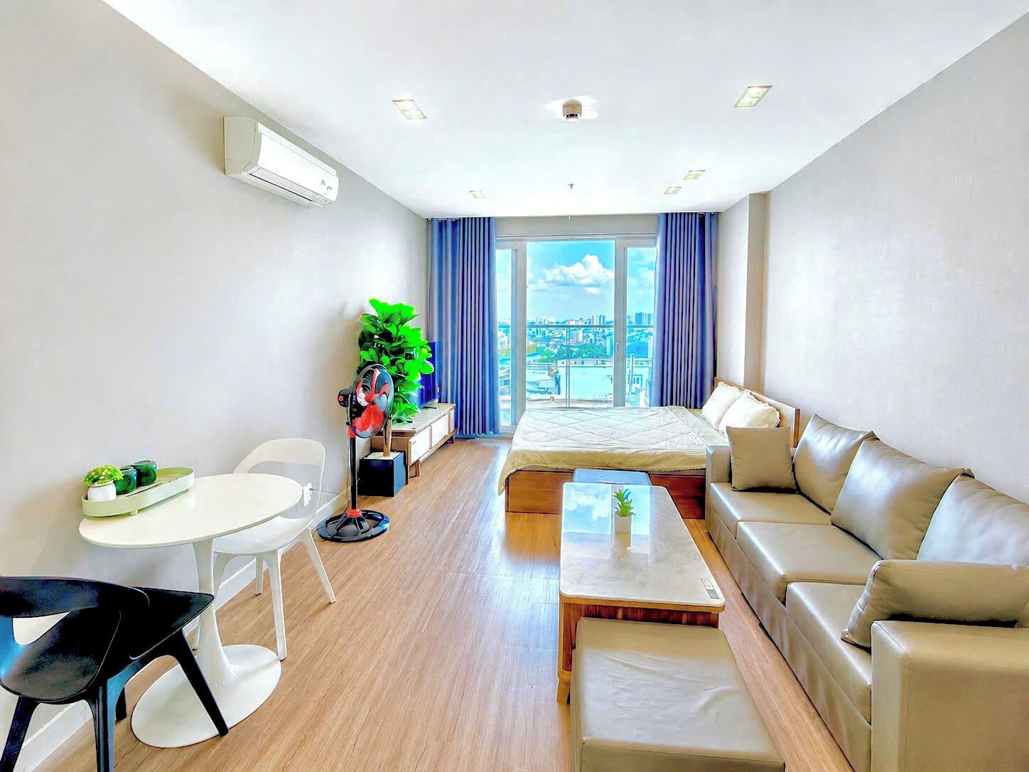 Una habitación de hotel moderna con cama, sofá, mesa de comedor y sillas.