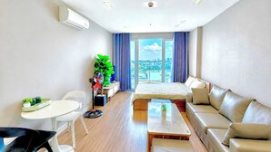 A modern hotel room with a bed, sofa, dining table, and chairs. - SKYHOME Apartment (Ho Chi Minh City)