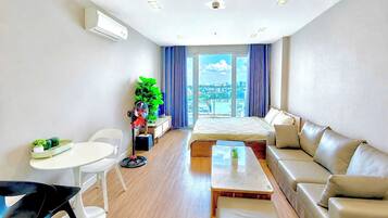 Una habitación de hotel moderna con cama, sofá, mesa de comedor y sillas.
