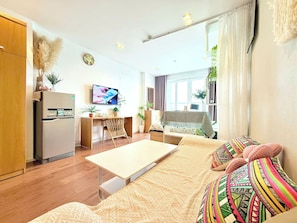 Ein modernes Wohnzimmer mit Küche, Essbereich und einer Couch mit bunten Kissen.