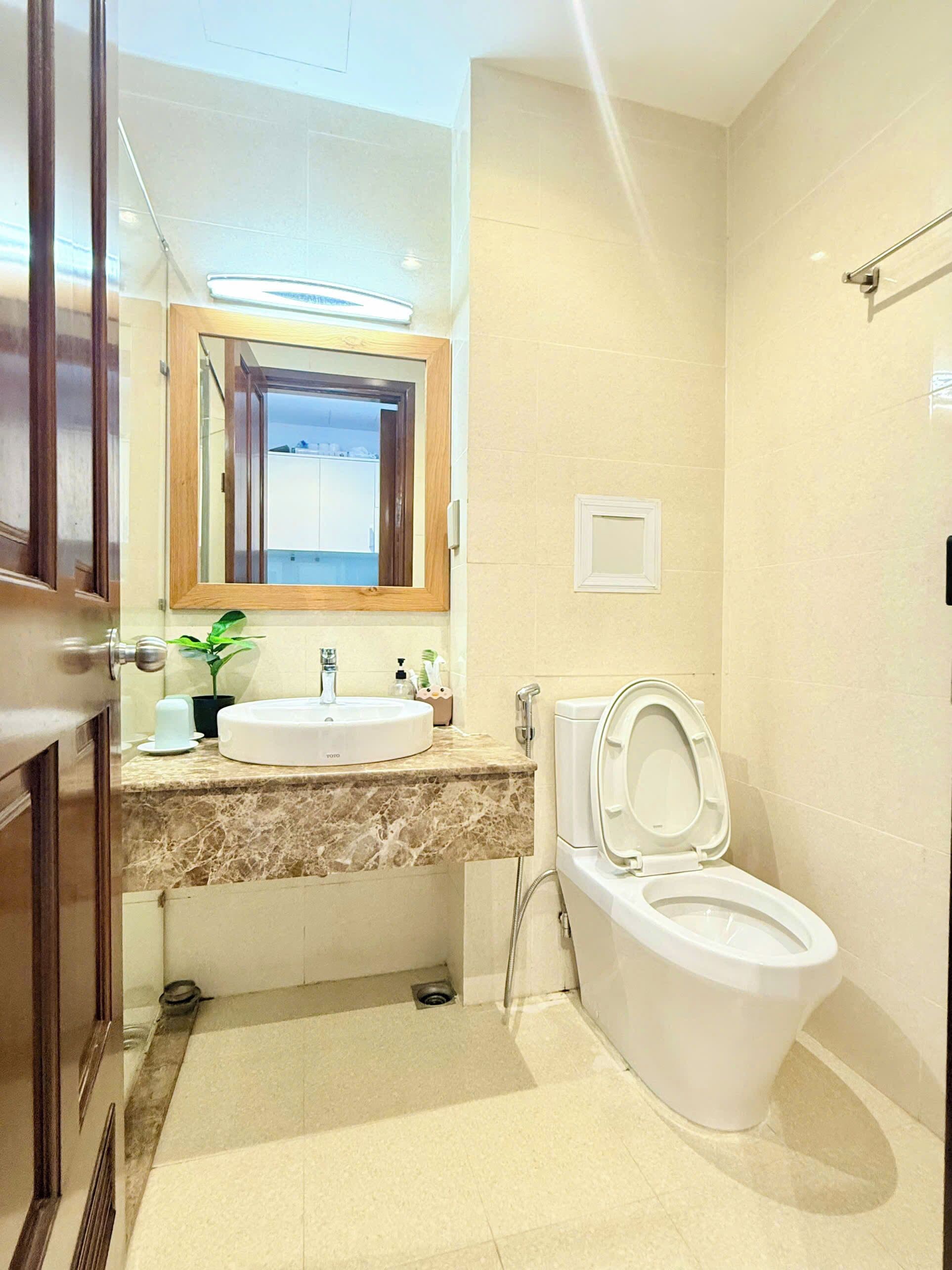 Ein Badezimmer mit Waschbecken, Spiegel, Toilette und einer Topfpflanze.