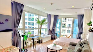 A modern hotel room with two beds, a dining table, a chair, a small round table, and a large window with curtains. - SKYHOME Apartment (Ho Chi Minh City)