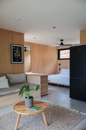 A modern room with a bed, a desk, a sofa, and a dining table.