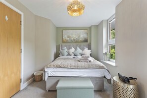 A bedroom with a bed, a hanging light fixture, a window, and a painting on the wall. - Finchdale Boutique Retreat (Wakefield)